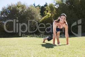 Essential steps to wellbeing. Portrait of an attractive brunette doing some stretching exercises on the grass.