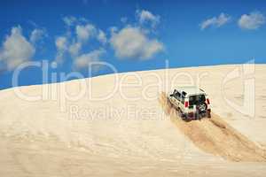 Making new roads. Shot of a heavy duty 4x4 driving along some sand dunes.