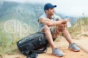 Taking a well-deserved break. Young hiker sitting down and taking a moment to rest.