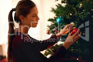 Deck the halls. Shot of an attractive young woman decorating a christmas tree.