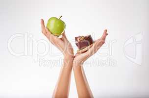 I know which one I want, but.... Studio shot of a woman deciding between healthy and unhealthy foods.