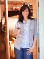 She knows her wines. Portrait of a pretty mature lady standing in a cellar with a glass of red wine.