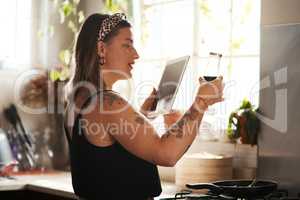 Know what you put into your body. Shot of a young woman using a digital tablet and reading the label on a bottle while preparing a meal.