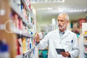 This doesnt belong here.... Cropped shot of a handsome mature male pharmacist using a tablet while working in the pharmacy.