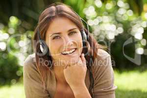 Enjoying the symphony of nature. Shot of a gorgeous young woman laying outdoors listening to music.