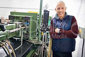 Everything is in perfect condition. Portrait of a mature man standing next to machinery in a factory.