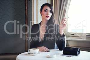 Luxury and style. Shot of a woman smoking a cigarette in a luxurious setting wearing classicly elegant attire.