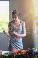 More ideas than time. A young woman in the process of making a flower arrangement.