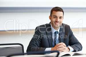 Ready to help. A handsome young businessman sitting at his desk with a smile.