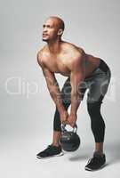 Getting his fitness on. Studio shot of an athletic young man working out with a kettle bell against a grey background.
