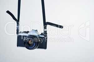 Film photography makes a comeback. Studio shot of a camera hanging by its strap.