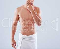 Abs-alicious. Cropped studio shot of a handsome bare chested young man with his waist wrapped in a towel.