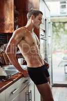 Luckily I have the whole day to myself. Shot of a muscular young man standing in the kitchen wearing only underwear while contemplating at home.
