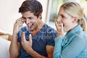 This is better than what wed hoped for. Shot of an excited young couple receiving wonderful news from a caller on their mobile phone.