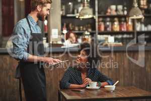 Would you like to hear about our specials. Shot of a young barista taking a customers order on a digital tablet at a cafe.