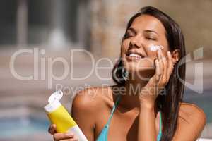 Theres no way Im peeling tomorrow. A beautiful young woman applying suntan lotion to her face.