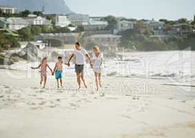 Enjoying the perfect family vacation. A happy young family walking down the beach together in the sunshine.