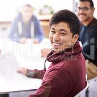 Meetings keep us on the same page. Portrait of a happy young man sitting in a meeting with his colleagues.