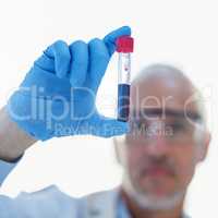 Observe closely.... Closeup shot of a male scientist examining a test tube in a lab.