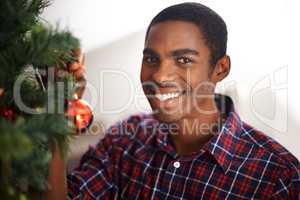 Christmas is my favourite time of year. Shot of a handsome young man standing by a christmas tree.