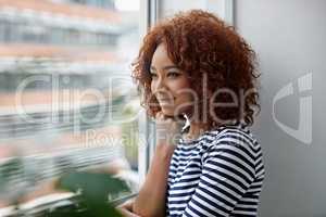 My career is going just how I planned. Shot of a young woman looking out of a window in an office.
