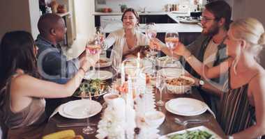 Gather your friends and let the good times flow. Shot of a group of young friends toasting with wine at a Christmas dinner party.