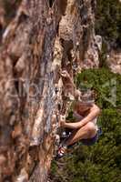 Nothing gets the heart going like scaling a mountain. Shot of a young woman climbing up a mountain rockface.