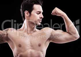 looking this good isnt easy.... Studio shot of a handsome bare-chested man flexing a bicep.