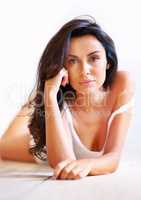 Intense look. Studio portrait of a brunette woman lying on a wooden floor.