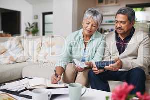 Budgeting works better when we do it together. Shot of an elderly couple working out a budget while sitting on the living room sofa.