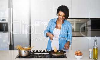 Her babys going to be a pasta lover. Shot of a pregnant young woman preparing a meal on the stove at home.