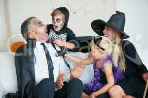 Best time of the year for frights. A cute family dressed up for Halloween all trying to scare each other.