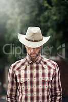 Kings have crowns, but a cowboy only has one hat. Shot of a handsome cowboy wearing a check shirt and stetson.