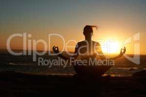 Finding peace and fulfillment. Silhouette of a woman doing a yoga pose against a setting sun.