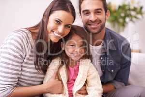 Theres an abundance of love in this home. Portrait of a happy young family sitting together at home.