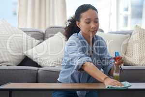 This spray is really good at protecting wood. Shot of a young woman cleaning down her wood coffee table at home.