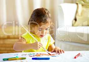 Every child is an artist. Shot of an adorable little girl making a mess while painting.