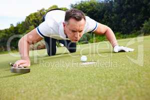 Its not cheating if nobody saw it. Shot of a handsome man trying to blow his golf ball into the hole.