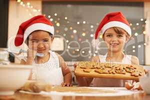 We made these Christmas cookies. Portrait of two little girls baking in the kitchen.