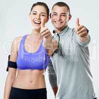 Say yes to a healthy relationship. Sporty young couple showing thumbs up in a studio.