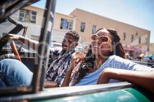 Its not about the destination, its about the ride. A happy young couple driving in a convertible on a bright summers day.