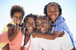 Its times like these you appreciate family. Two parents giving their children a piggyback while on the beach.