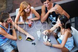 Relaxing with all the gang. Group of teens enjoying milkshakes and beverages while at an outdoor restaurant - high angle.
