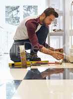 His DIY skills will floor you. Shot of a man laying floor tiles.