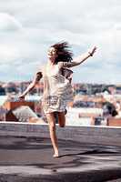 Letting go and living life. Pretty young woman dancing whimsically on a rooftop.