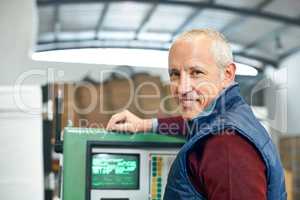 This panel is the nerve center of the factory. Portrait of a mature man standing next to machinery in a factory.