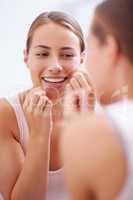Dental hygiene is a priority. A young woman flossing her teeth.