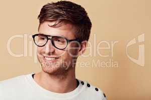 Hes got a carefree outlook on life.... Studio headshot of a stylishly-dressed young man smiling and wearing glasses.