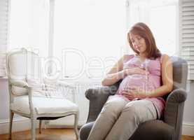 Motherhood is a wonderful thing. A glowing pregnant woman looking at her swelling baby bump lovingly - Copyspace.