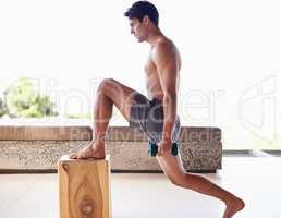Fitness is about daily commitment. A muscular young man doing strength exercises with dumbbells at home.